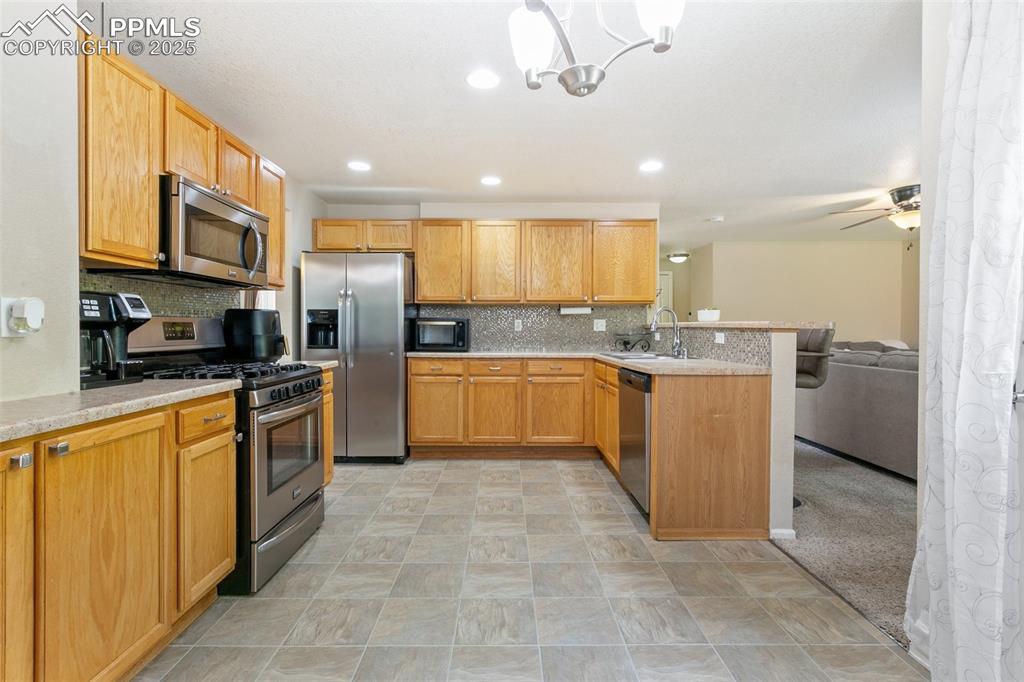 Image 13 of 46: Kitchen featuring stainless steel appliances, a peninsula, light countertop