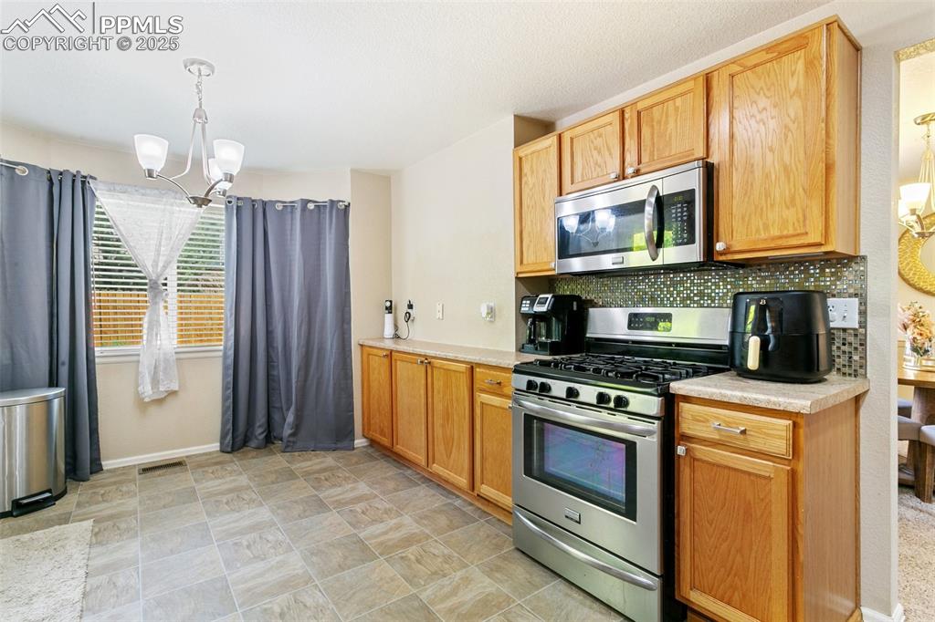 Image 15 of 46: Kitchen featuring appliances with stainless steel finishes, a chandelier, l