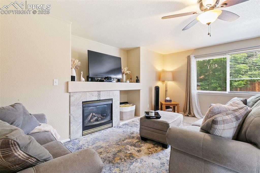 Image 18 of 46: Living area featuring a tiled fireplace and a ceiling fan