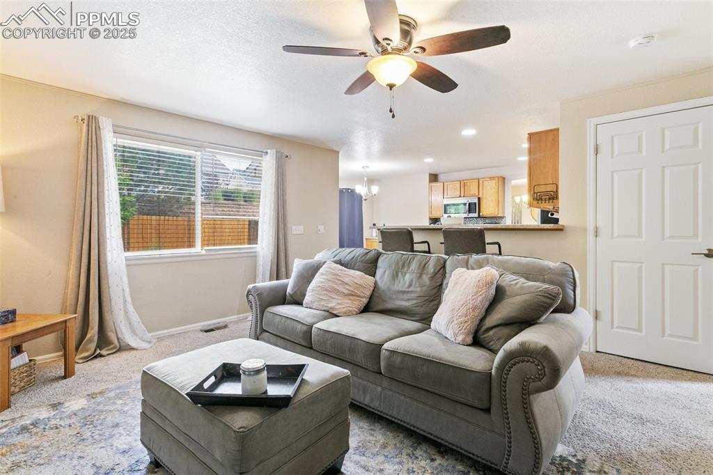 Image 19 of 46: Living room with ceiling fan, light carpet, a chandelier, and recessed ligh