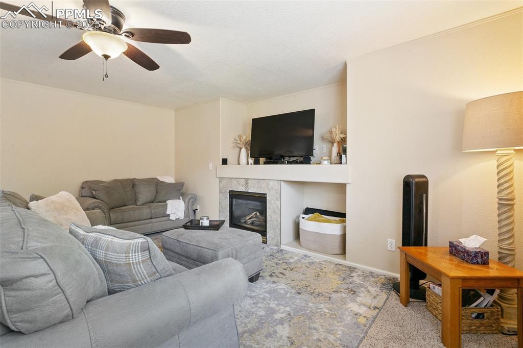 Image 21 of 46: Living area with a ceiling fan, carpet, and a tiled fireplace