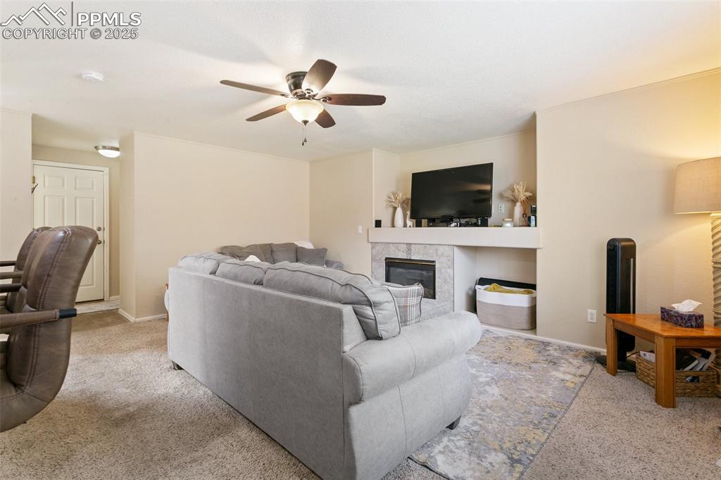 Image 22 of 46: Carpeted living area with a fireplace and a ceiling fan