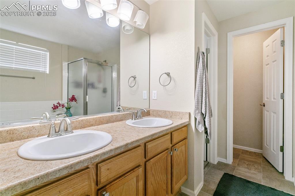 Image 31 of 46: Bathroom with a stall shower, double vanity, and a tub to relax in
