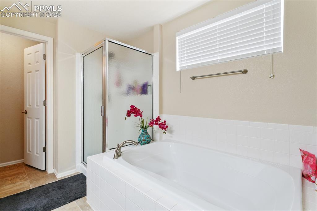 Image 32 of 46: Bathroom with a stall shower, a bath, and tile patterned flooring