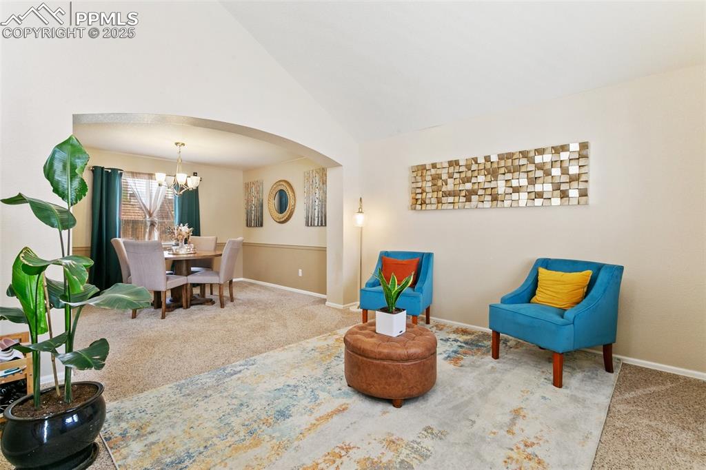 Image 4 of 46: Living area featuring arched walkways, carpet floors, vaulted ceiling, and