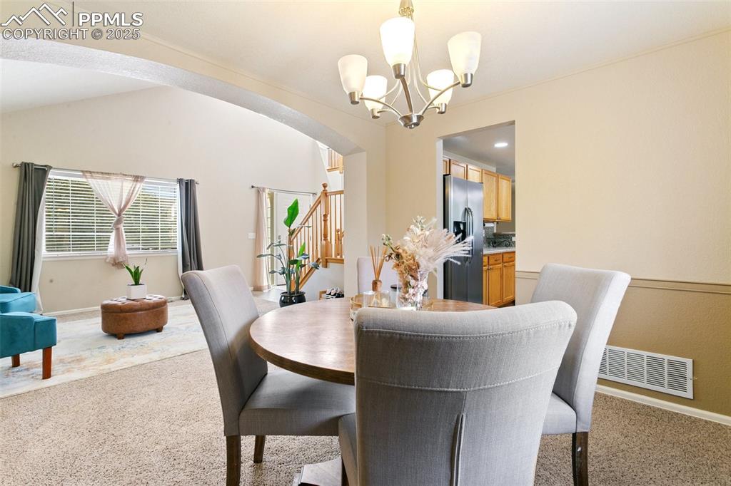 Image 8 of 46: Dining space featuring light colored carpet, arched walkways, stairway, and