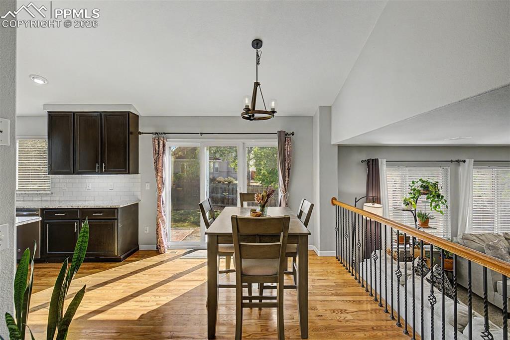Image 14 of 49: A sun-drenched dining nook off the kitchen features hardwood floors, a pend