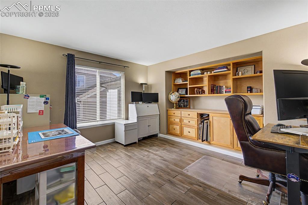 Image 20 of 49: Tucked behind French doors, the main-level home office features built-in sh