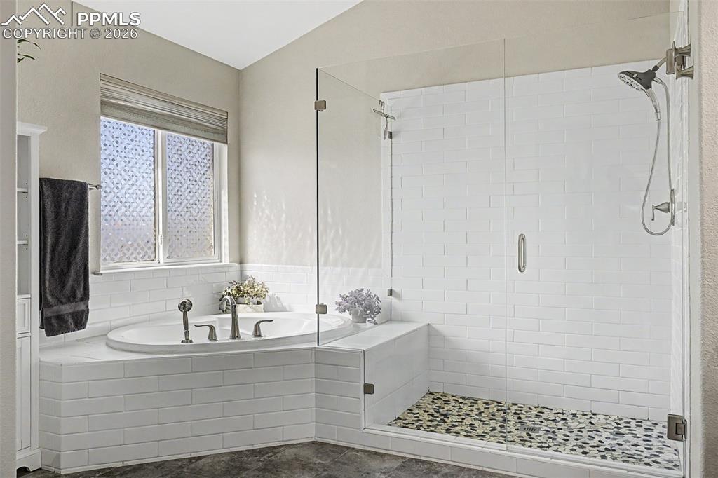 Image 23 of 49: The spa-like primary bathroom features a deep soaking tub framed in subway 