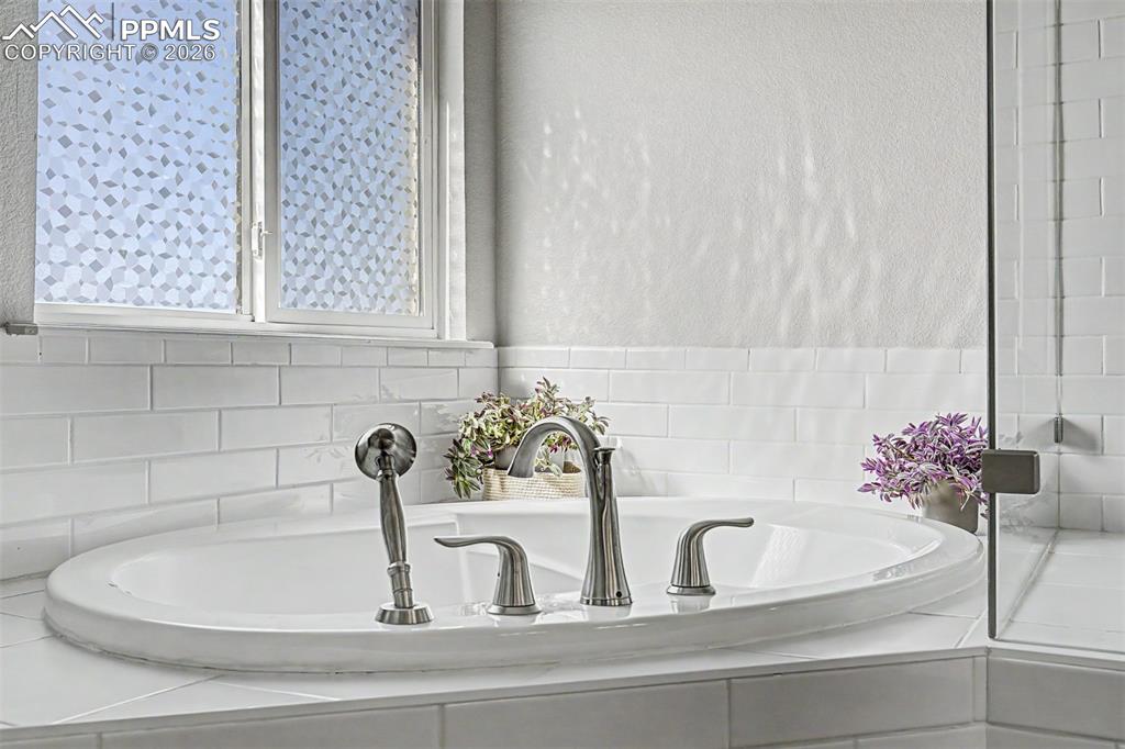 Image 24 of 49: The soaking tub reveals its beautifully appointed fixtures, frosted privacy