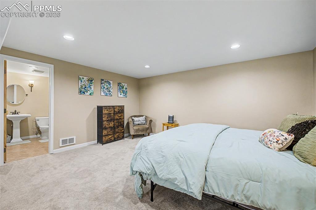 Image 29 of 49: The spacious basement bedroom offers recessed lighting, plush carpet, and d