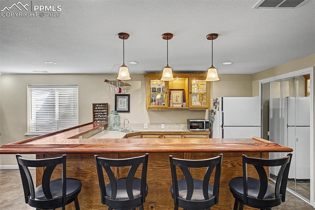 Image 32 of 49: Downstairs, a handsome wood-topped bar with seating for four sets the tone 
