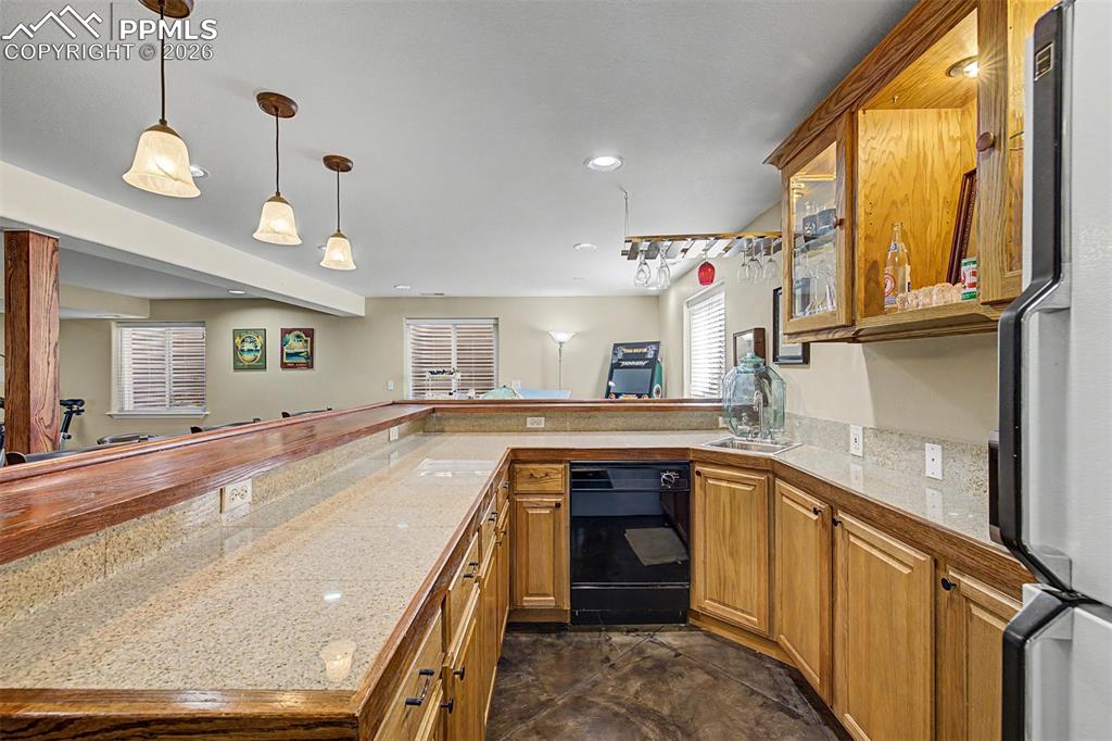 Image 33 of 49: Granite countertops, warm oak cabinetry, and pendant lighting give the base