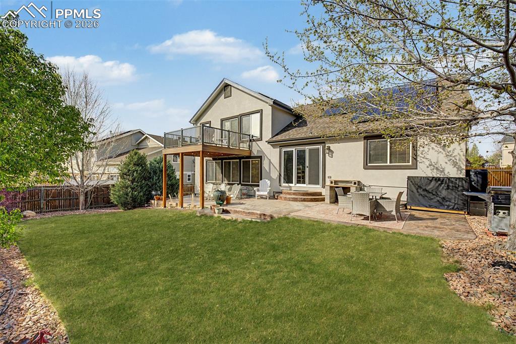 Image 39 of 49: Looking across the wide, well-landscaped backyard, the home