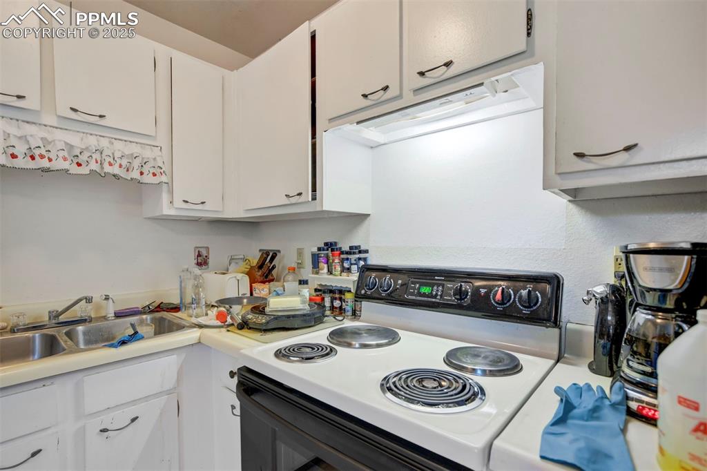 Image 11 of 38: Kitchen featuring electric stove, light countertops, white cabinetry, and e