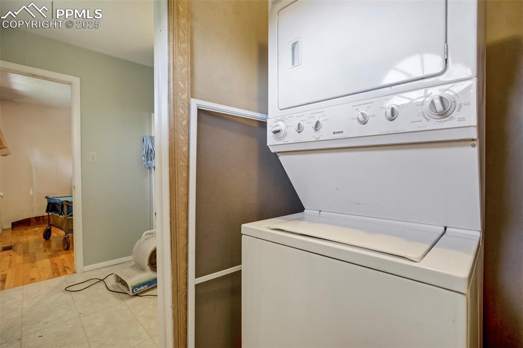 Image 12 of 38: Laundry area featuring tile patterned floors and stacked washer / drying ma