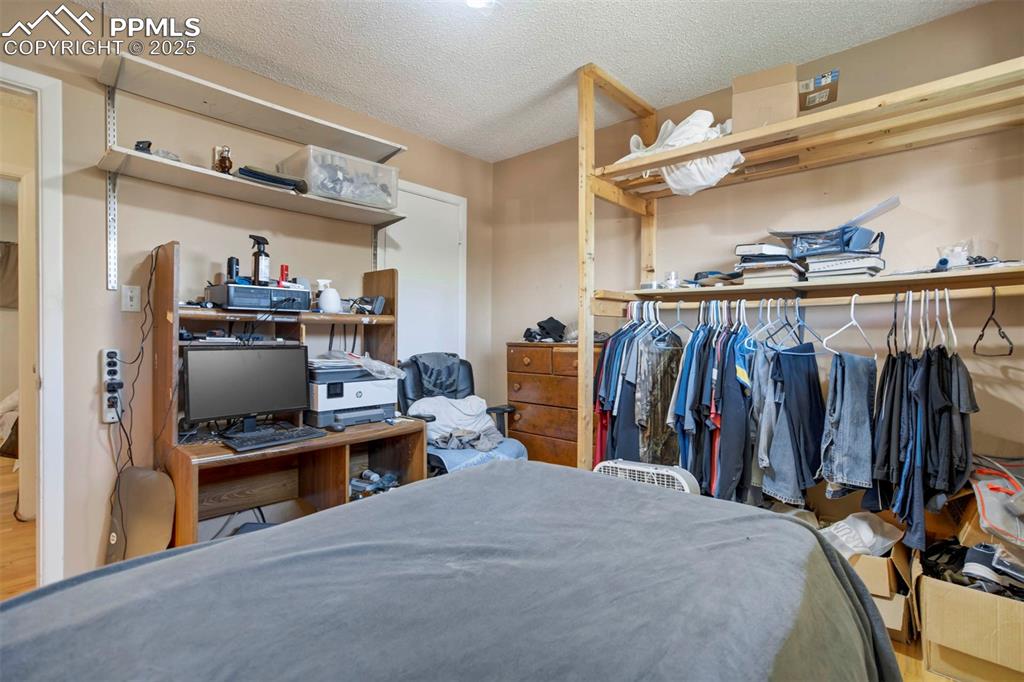 Image 18 of 38: Bedroom with a textured ceiling, wood finished floors, and a desk