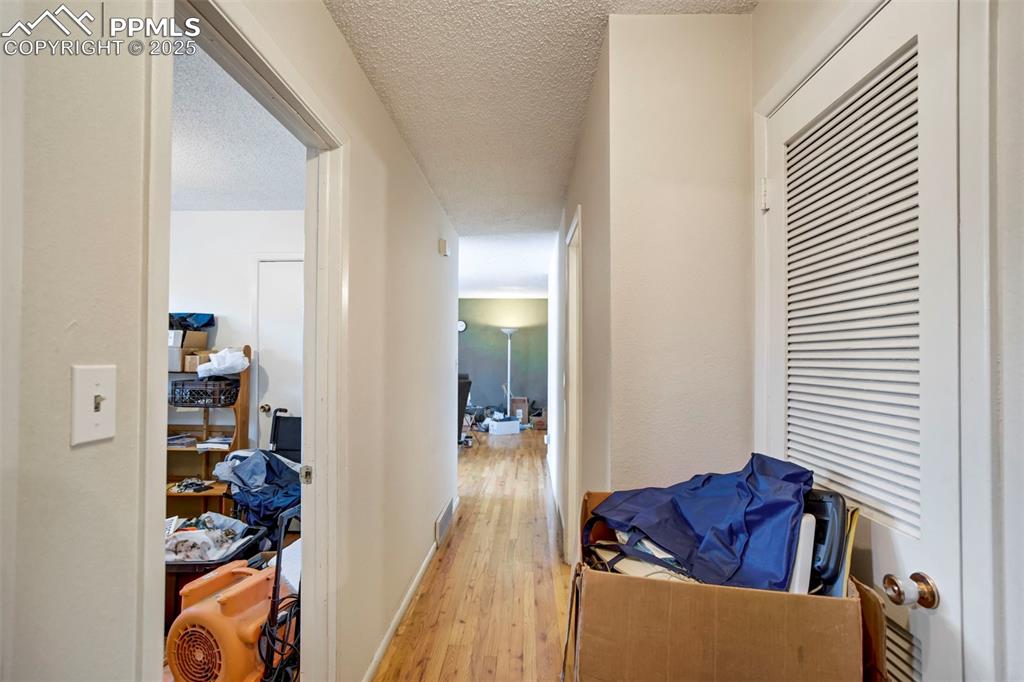 Image 21 of 38: Corridor with hardwood / wood-style flooring and a textured ceiling