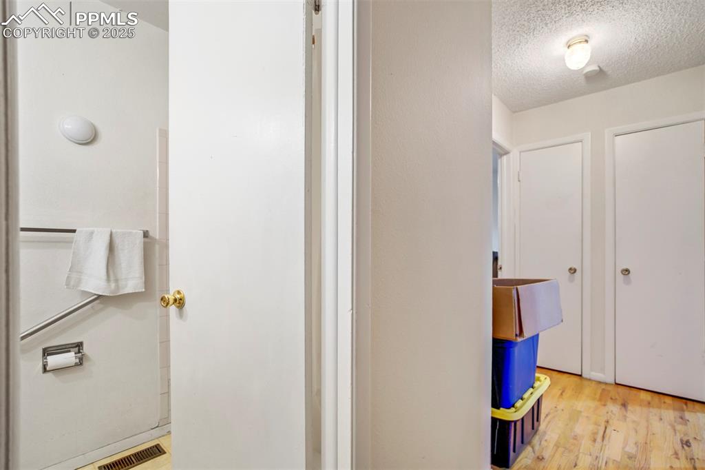Image 24 of 38: Hallway featuring light wood-type flooring and a textured ceiling