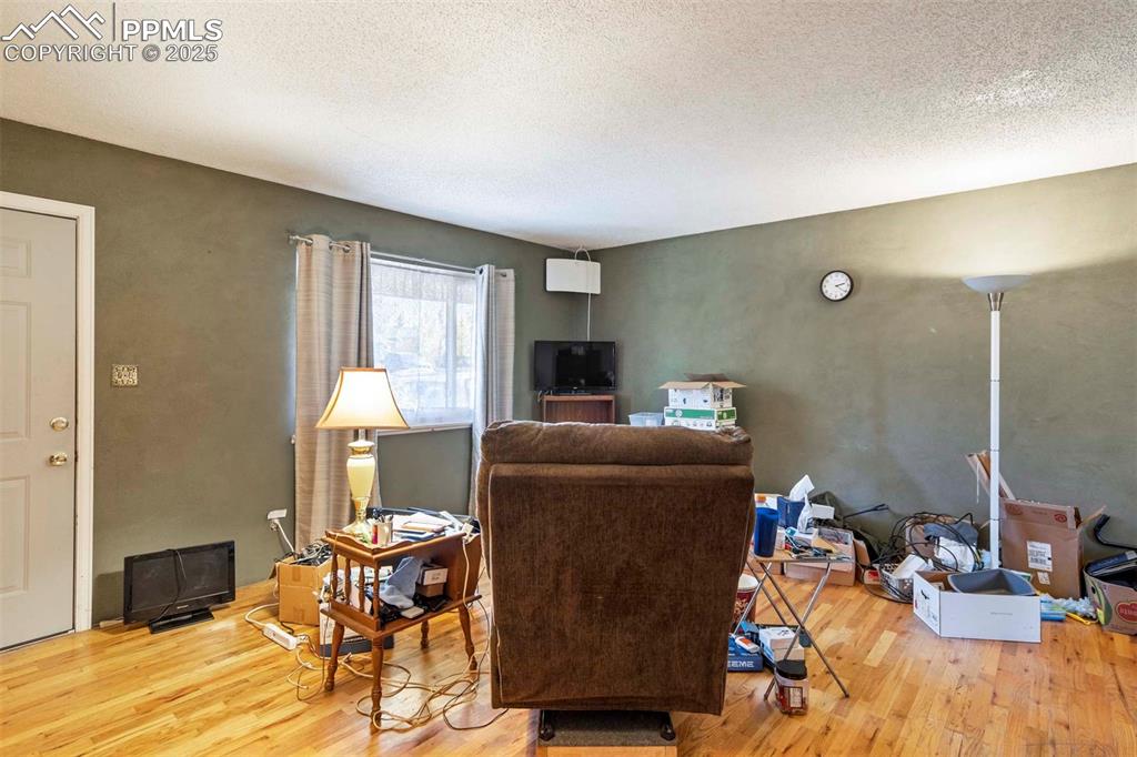 Image 4 of 38: Living room with a textured ceiling and light wood-type flooring