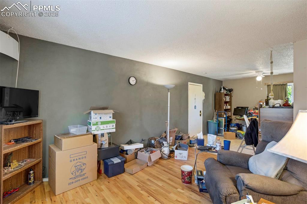 Image 5 of 38: Living area featuring light wood-type flooring, a textured ceiling, and a c