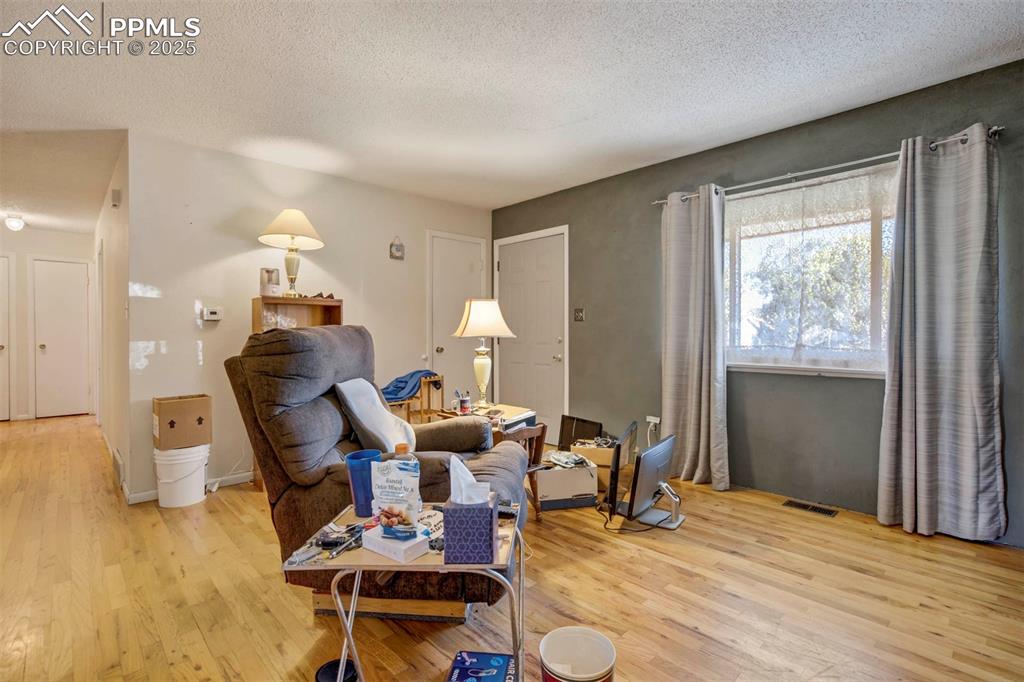 Image 6 of 38: Living area featuring a textured ceiling and light wood-type flooring
