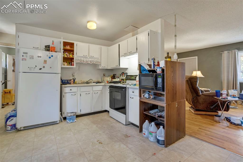 Image 8 of 38: Kitchen with white appliances, light countertops, white cabinetry, open she
