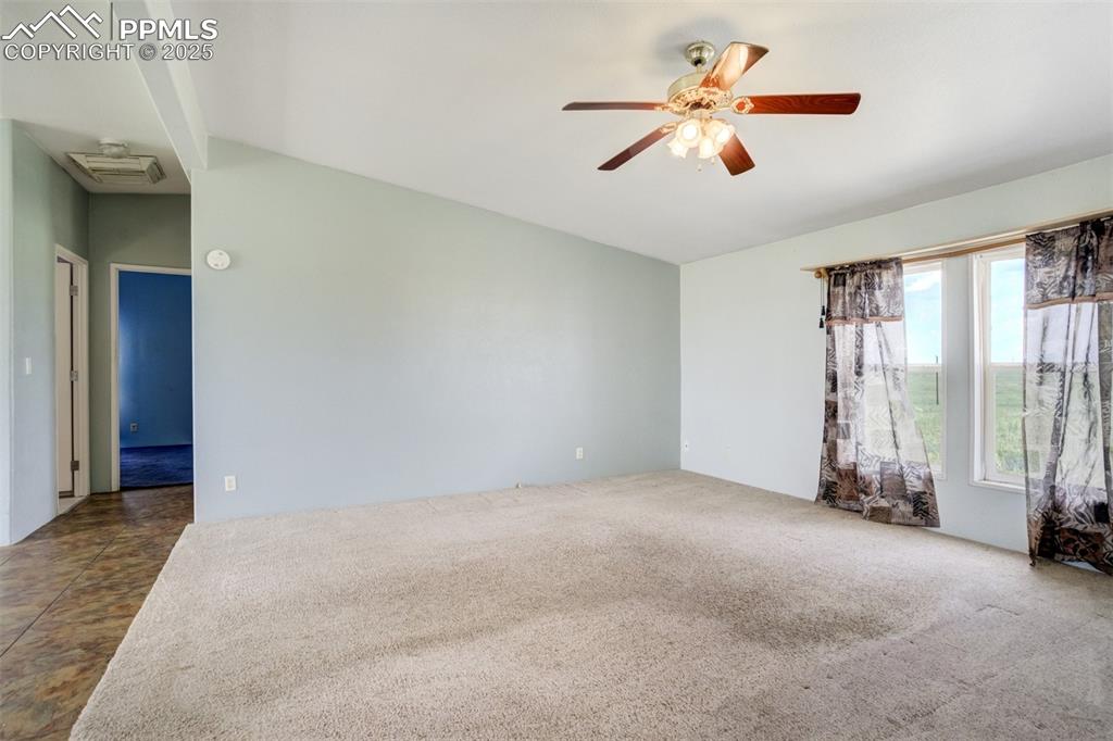 Image 10 of 49: Spare room with ceiling fan, dark carpet, and lofted ceiling
