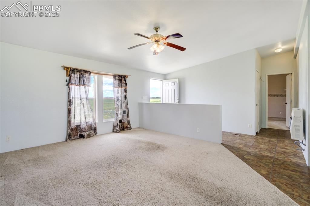 Image 11 of 49: Carpeted spare room with ceiling fan and vaulted ceiling