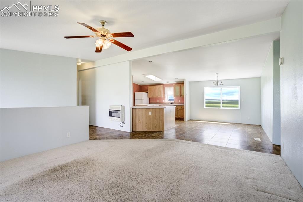 Image 12 of 49: Unfurnished living room with heating unit, carpet floors, ceiling fan, and 