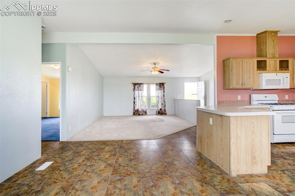 Image 14 of 49: Kitchen featuring white appliances, light brown cabinetry, light countertop