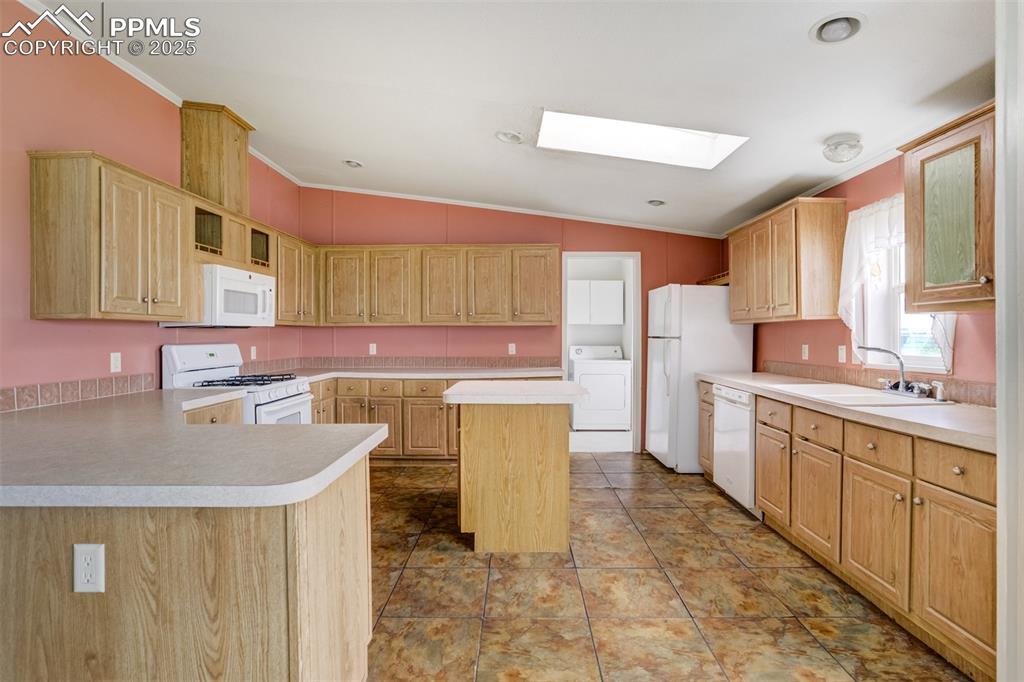 Image 15 of 49: Kitchen with white appliances, washer / dryer, ornamental molding, a skylig