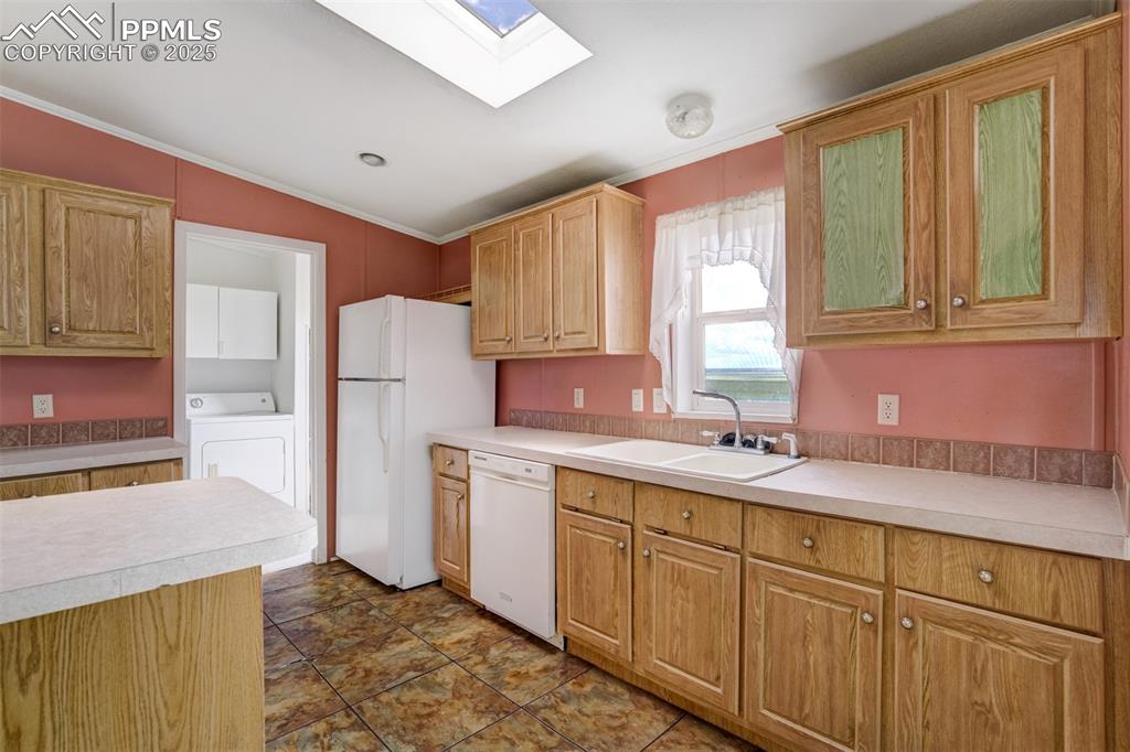 Image 16 of 49: Kitchen featuring white appliances, washer / clothes dryer, a skylight, orn