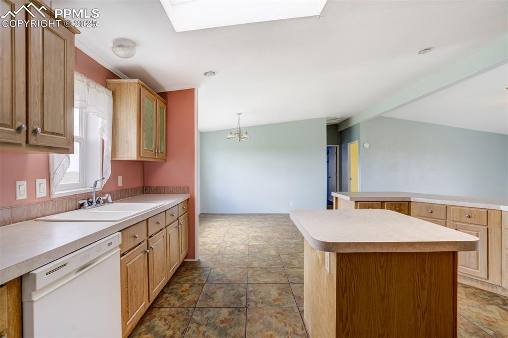 Image 18 of 49: Kitchen with dishwasher, light countertops, stone finish floors, and a cent