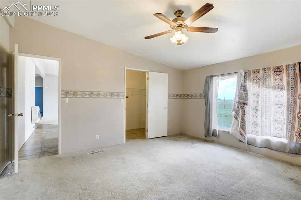 Image 21 of 49: Unfurnished bedroom with light carpet, lofted ceiling, a walk in closet, a 