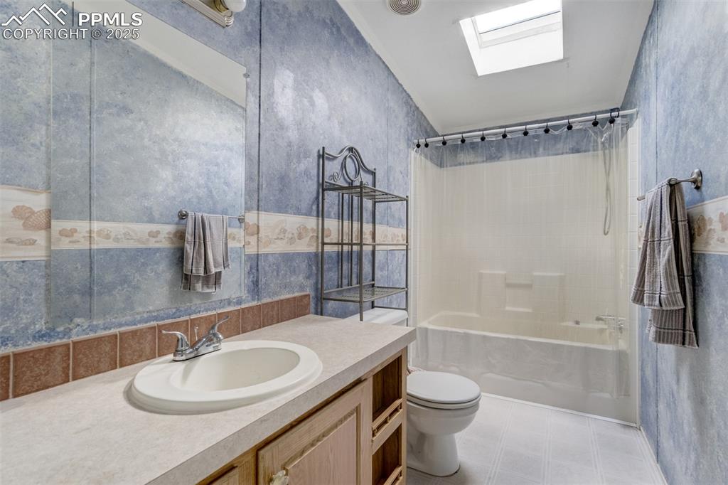 Image 29 of 49: Full bathroom featuring a skylight, vanity, and shower / tub combo