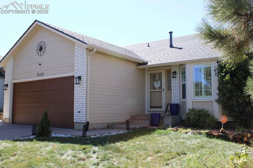 Caption: Ranch-style house featuring brick siding, an attached garage, a shingled roof, a front yard, and dri
