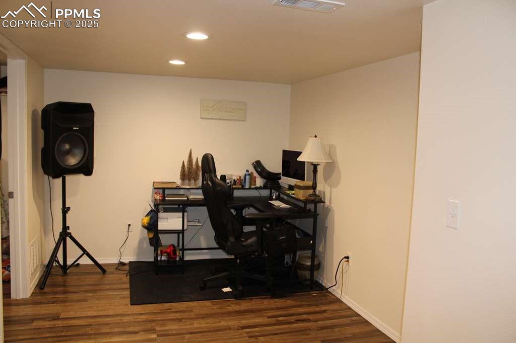 Image 28 of 30: Office space with dark wood-style flooring and recessed lighting