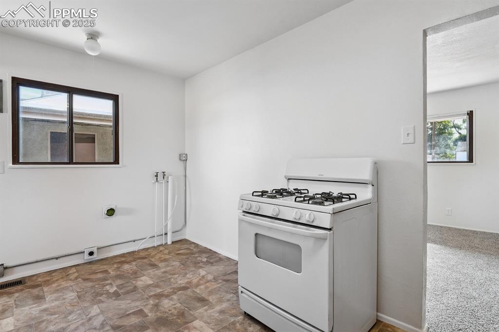 Image 10 of 33: Kitchen featuring white range with gas cooktop and stone finish flooring