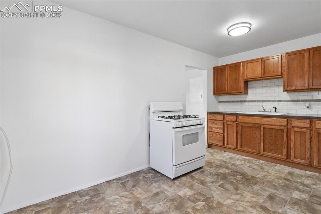 Image 12 of 33: Kitchen featuring stone finish floors, white range with gas cooktop, tastef
