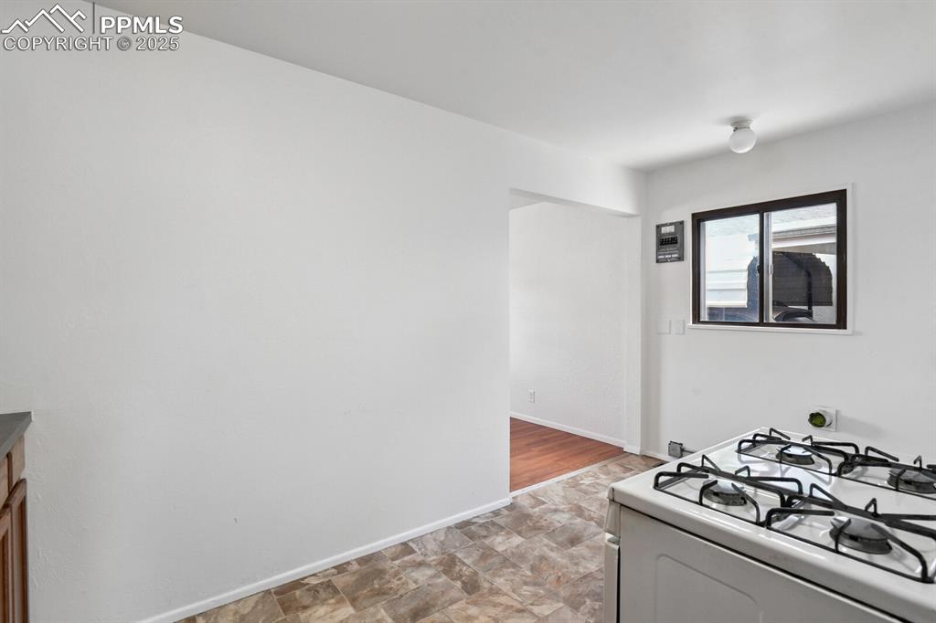 Image 9 of 33: Kitchen featuring white gas range oven and stone finish flooring
