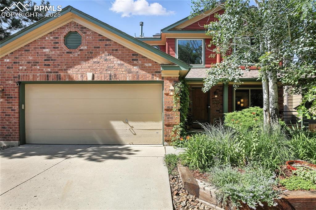 Image 2 of 50: View of front of property featuring driveway, brick siding, and a garage