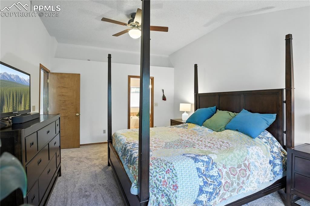 Image 20 of 50: Bedroom with light colored carpet, lofted ceiling, and a ceiling fan