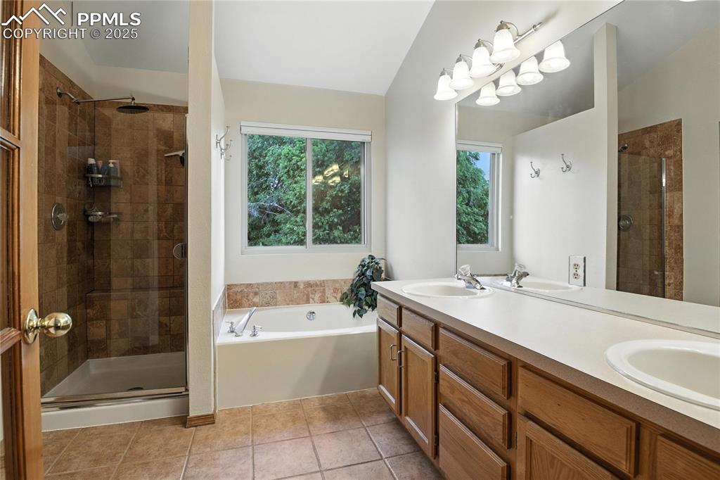 Image 21 of 50: Bathroom featuring a shower stall, a bath, double vanity, and tile patterne
