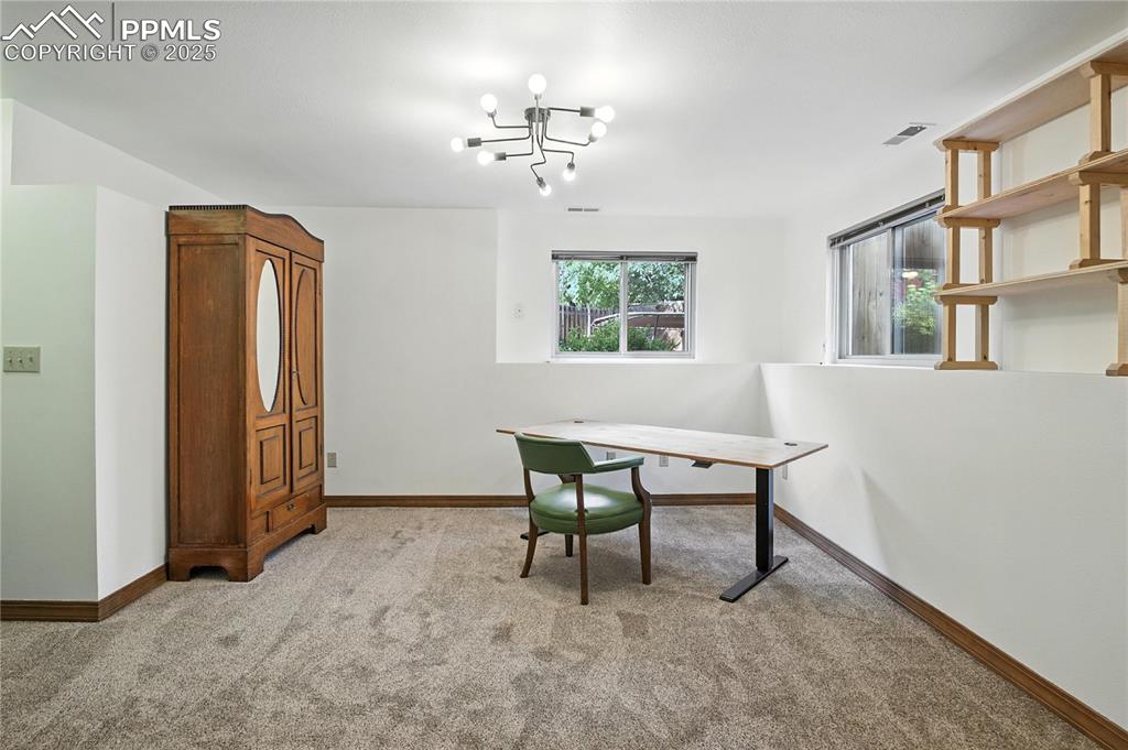 Image 31 of 50: Office with light colored carpet and a chandelier