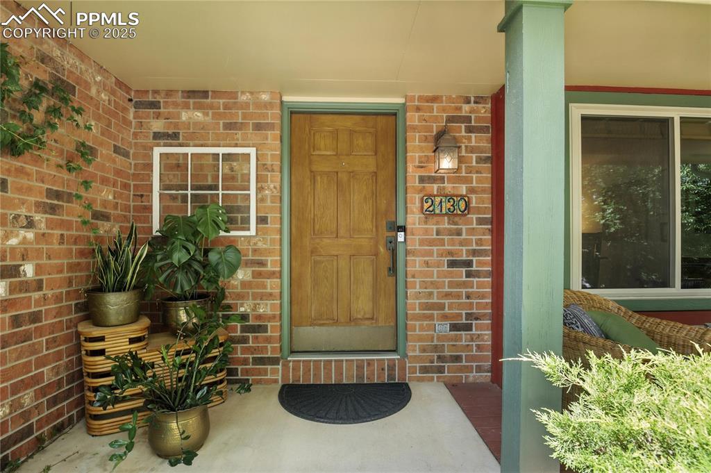 Image 4 of 50: Property entrance with brick siding and a porch