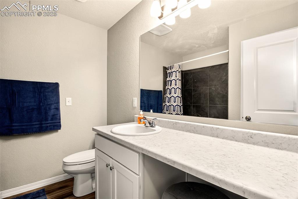 Image 27 of 31: Upstairs full bathroom with tile surround tub/shower, makeup station w/seat