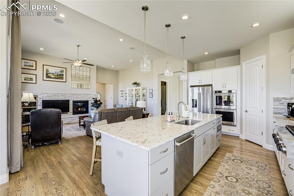 Image 4 of 50: Light-filled great room anchored by a stone-surround gas fireplace and inte