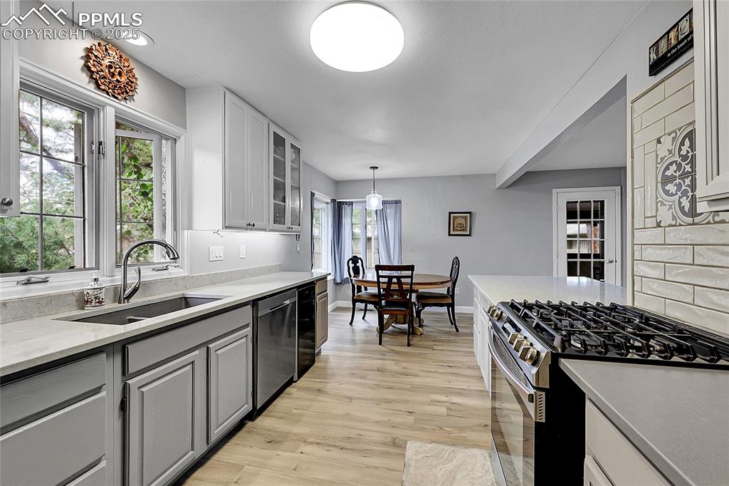 Image 13 of 36: Kitchen featuring stainless steel appliances, gray cabinets, light wood-sty