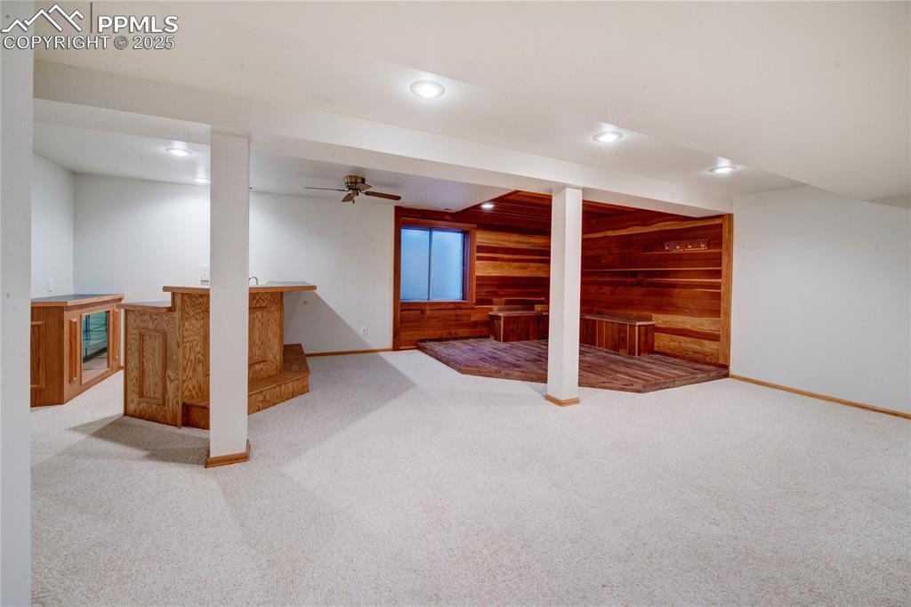 Image 28 of 36: Finished below grade area with wood walls, wet bar, recessed lighting, and 